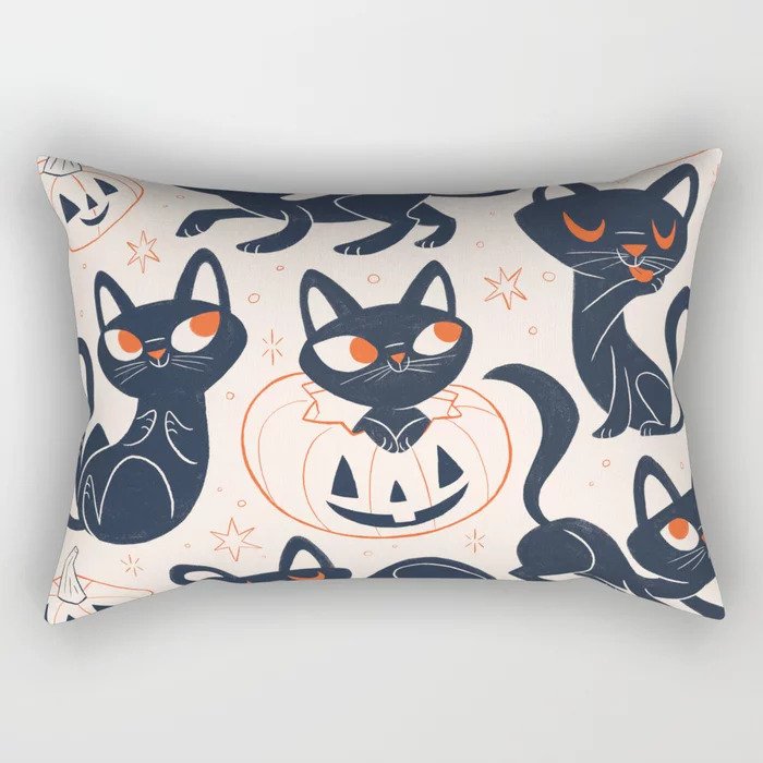 Picture of a rectangular throw pillow featuring illustrations of a black cat in various poses and one of them is coming out of an orange line art pumpkin.